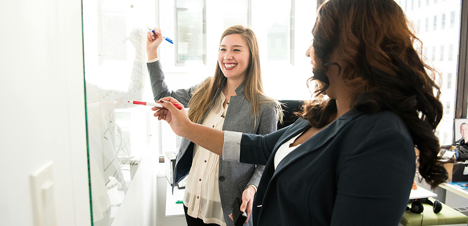 Bright, airy office environment where two smiling women are working